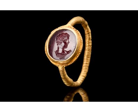 Ca. early 3rd century AD.A gold ring consisting of a round hoop adorned with ribbed details. The bezel of the ring is embelli