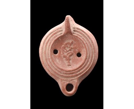 Ca. 100-200 AD.A moulded pottery oil lamp sitting on a ring base with marker's mark. This oil lamp boasts smooth side walls a