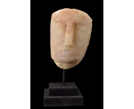 Ca. 200 BC - 100 AD.An alabaster face stele depicting a stylized human face. The facial features are defined but abstracted, 