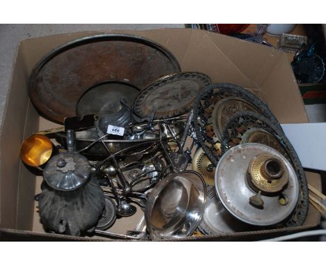 A large box containing old pewter, large oil lamp, oriental metal trays and plates, cutlery etc.