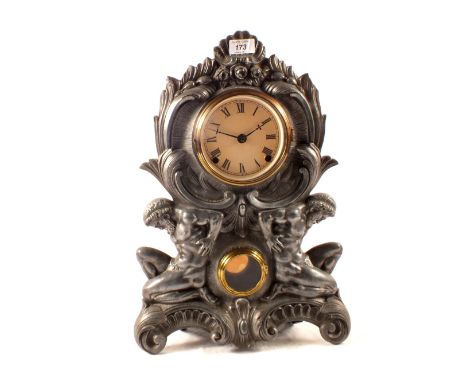 A striking mantel clock with cast metal front flanked by naked kneeling men (with fig leaves)