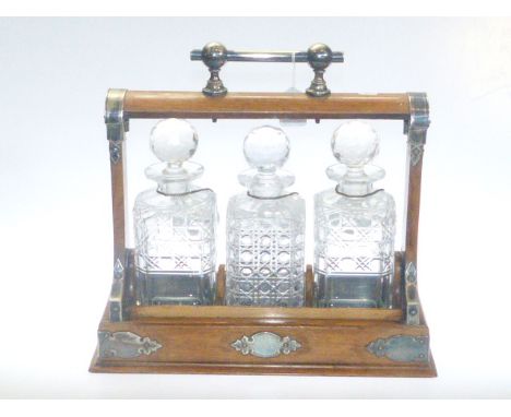 Oak and silver plated three bottle tantalus with ceramic label