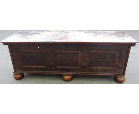 A 16th century Cypresswood trunk, the plank top over a blind carved front, on later bun feet, 191cm wide.