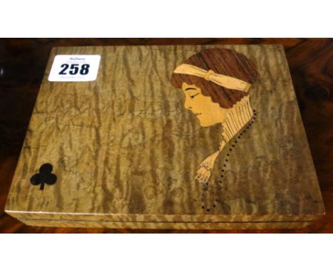 An Italian marquetry playing card box, the hinged top with a club motif and a profile portrait of a lady in Art Deco style. 