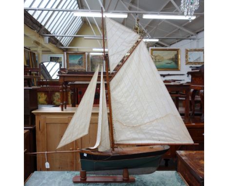 A vintage wooden pond yacht with black and green painted hull and lead keel, on a stained beech stand, 86cm wide x 100cm high