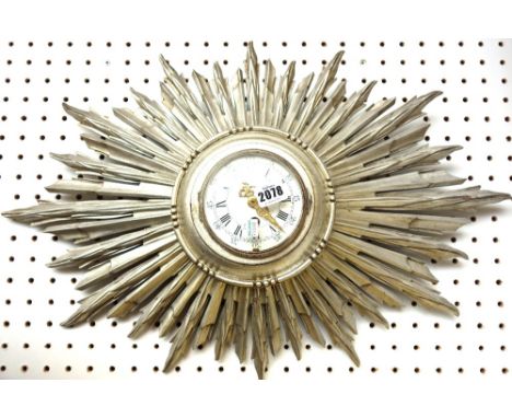 A French silvered, carved wood sunburst wall clock, 20th century, with enamel dial and carved body, (a.f.), 62cm wide. 