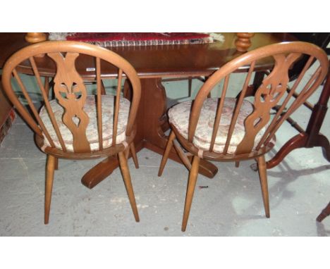 An Ercol dining table with four matching stick back chairs.