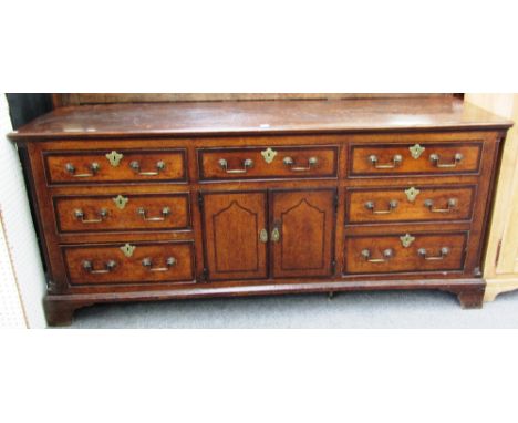 An 18th century oak and mahogany banded dresser base, with single drawer over cupboards flanked by three drawers either side,