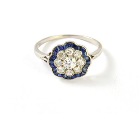 A diamond and sapphire set cluster ring, mounted with the principal cushion shaped diamond at the centre, in a surround of ei