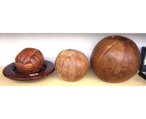 A leather clad medicine ball by J. Salter and Son, one smaller medicine ball, a vintage leather football, and a turned Red Ri