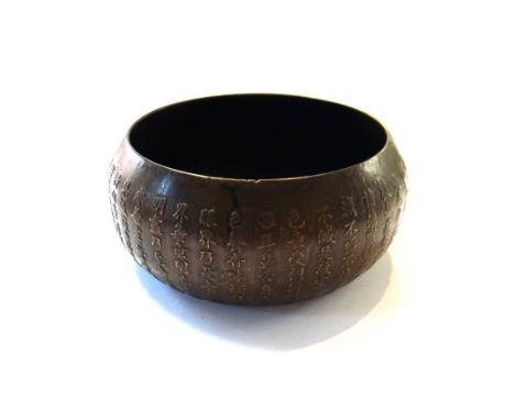 A Chinese small bronzed metal bowl, of squat form, the sides decorated in relief with rows of calligraphy, 10cm. diameter, se