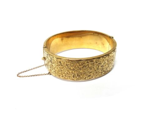 A 9ct gold oval hinged bangle, the front with feathered scroll engraved decoration, presentation inscribed at the back, Chest