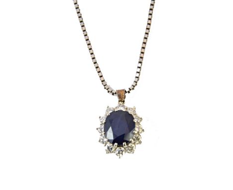 A sapphire and diamond set oval cluster pendant, claw set with the oval cut sapphire at the centre, within a surround of twel