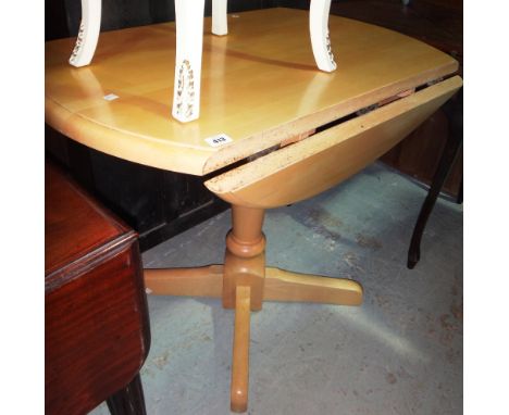 A 20th century beech drop flap pedestal dining table, together with two pine stick back dining chairs.