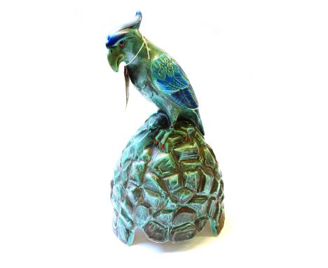 A Doulton pottery speaker cover, circa 1920, manufactured for Artandia Ltd and modelled as a Cockatoo atop a rocky mound (a.f