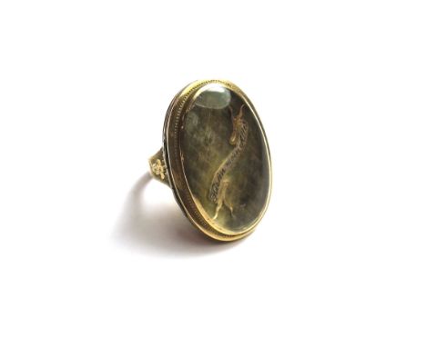 A gold oval locket ring, glaze to the front with an interwoven hair locket, with a black enamelled scroll detailed HIERIN MEI