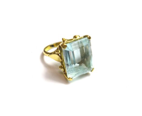 A gold ring, claw set with a rectangular step cut aquamarine, between split shoulders, ring size K.