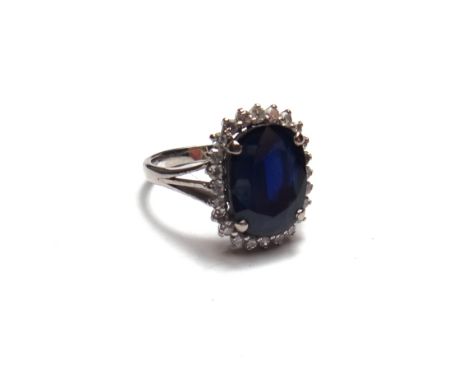 A sapphire and diamond set oval cluster ring, claw set with the oval cut sapphire at the centre, within a surround of small c