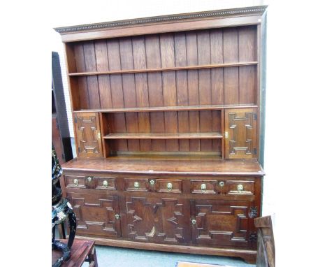 A large oak dresser, the enclosed three tier plate rack with pair of cupboards, over a geometric moulded base with three draw