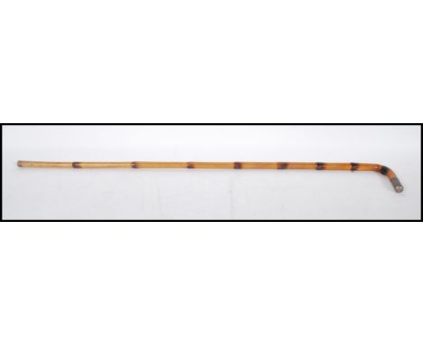 An early 20th Century bamboo walking stick cane having a crook neck with a silver tip engraved with initials.&nbsp;
