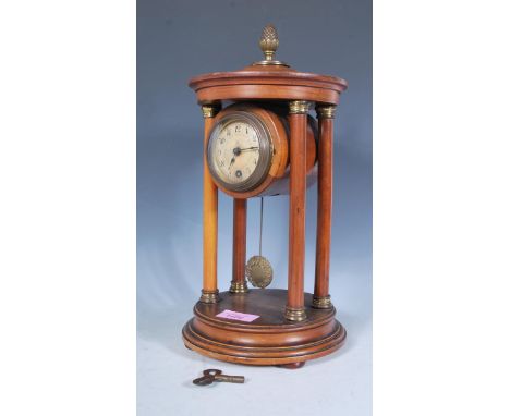 An early 20th Century mahogany pendulum portico mantel clock raised on a round plinth base, the round clock face raised betwe