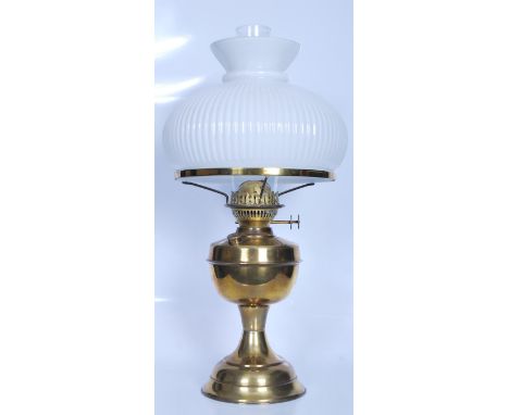 A large 20th Century brass oil lamp raised on a round plinth base with a bulbous reservoir to the centre of the column culmin