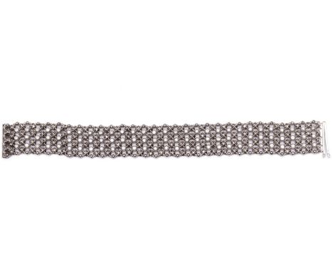 Engeland, 18 kt. witgouden armband, opgebouwd uit ovale met elkaar verweven schakels, op de kruisingen bezet met briljant ges