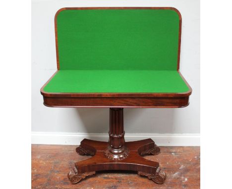 A George IV mahogany folding card table, the top enclosing a green playing baize, raised on turned and reeded support to quad