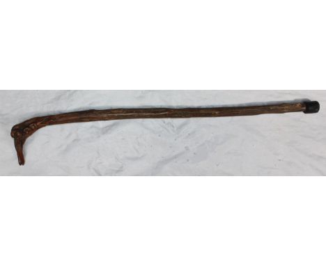 A stained wooden walking stick of naturalistic form, the handle carved with monkeys amidst foliage, overall length 82cm 