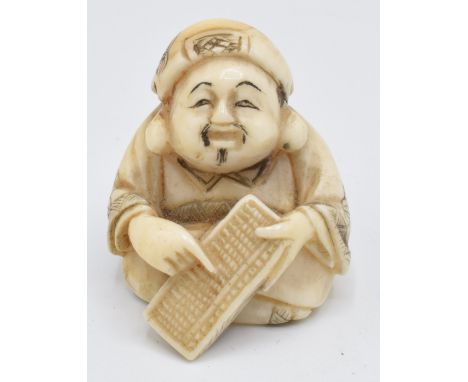 An early 20thC Japanese ivory netsuke depicting a man using an abacus, 3cm&nbsp;