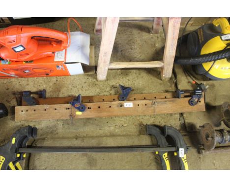 A pair of sash clamps mounted to wooden board