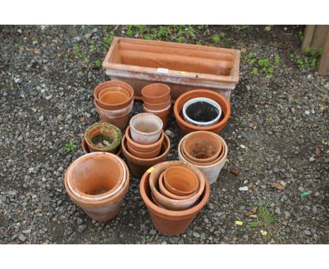 A terracotta plant trough and a quantity of various sized terracotta plant pots