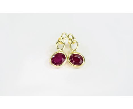 Ruby Pair of Drop Earrings, each having a bezel set, oval cut ruby of 2.25cts, on the diagonal, beneath two graduated ovals i