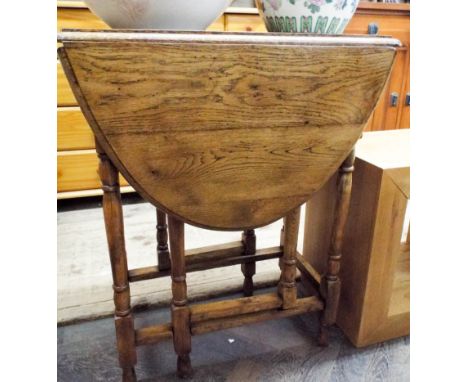 A 1930's golden oak drop leaf gate legged dining table of small size