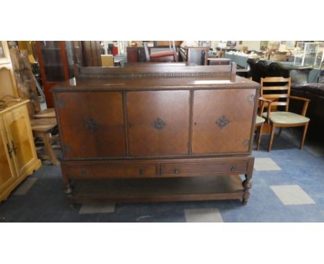 An Edwardian Oak Side Board with Galleried Top, Shelved Interior with Cellarette Slide and Two Base Drawers Over Pot Board Sh