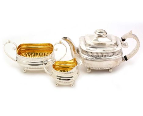 A George III silver matched three-piece tea set, with part-fluted, rounded oblong bodies and ball feet; the milk jug and suga