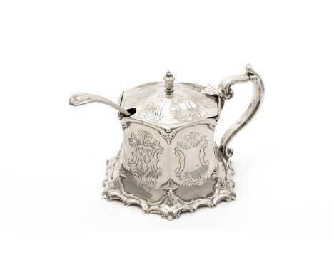 A Victorian silver mustard pot, with an engraved hexagonal body, and a flared scroll-decorated base, crested, glass liner, by