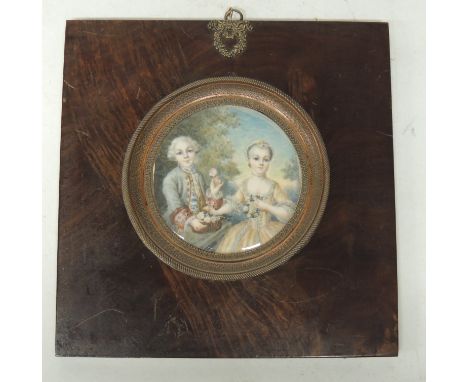 A decorative circular portrait on ivorine of two children in 18th Century costume in square wood frame with decorative copper