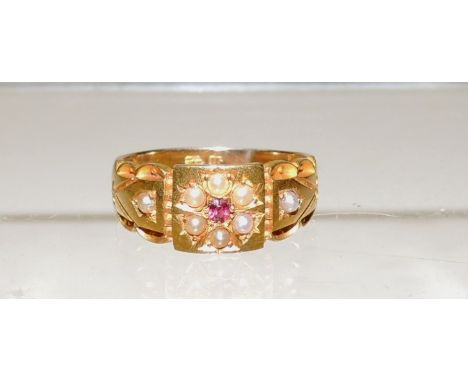 A Victorian 15ct gold ladies dress ring, set with a small central ruby within a surround of seed pearls.  Ring size N. 