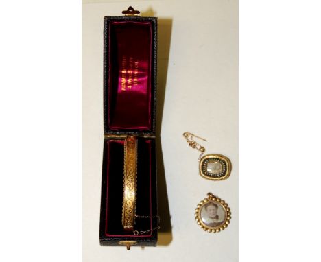 A cased 9ct gold Victorian bangle, decorated with gold swirls on a matt background, 10.3g approx.  A gold photo locket set wi