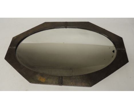 An Arts and Crafts wall mirror of shaped rectangular form having planished brass frame and bevelled plate, 50cms x 84cms
