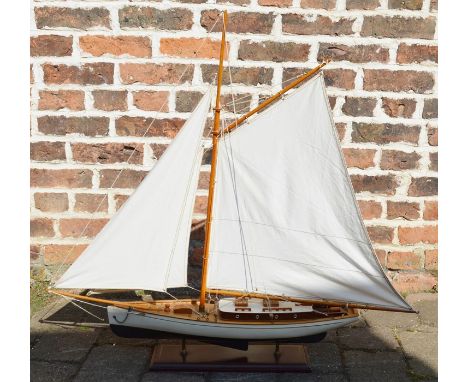 Modern model yacht with sail and rigging on fixed wooden stand, length of yacht 49cm