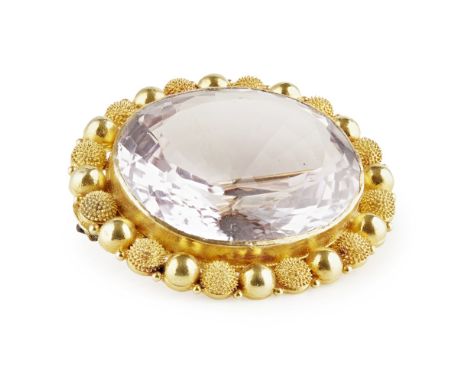 A large amethyst set brooch  collet set with a large oval mixed cut amethyst, in a beaded border with textured detail, unmark