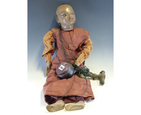 A BURMESE PUPPET DRESSED AS A BUDDHIST MONK WITH A BOWL IN ONE HAND.   H 62cms.