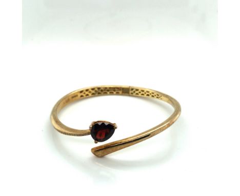 FEI LIU FINE JEWELLERY. A SILVER GILT HALLMARKED HINGED BANGLE SET WITH A PEAR CUT GARNET. WEIGHT 19.77 grams