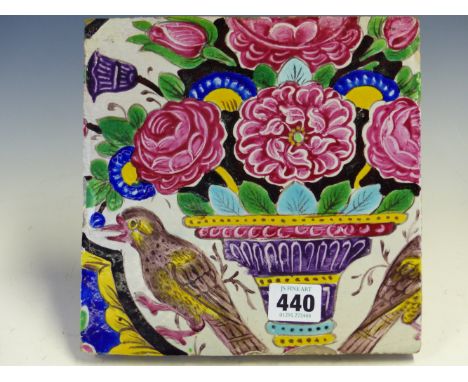 A PERSIAN CUERDA SECA TILE PAINTED WITH A BIRD FLANKING A VASE OF PINK FLOWERS.   20.5 x 20cms.
