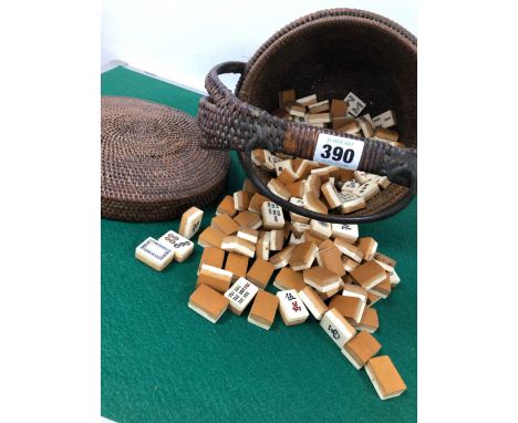 A CHINESE COVERED BASKET CONTAINING BONE AND BAMBOO MAHJONG TILES, THE BASKET HANDLE RAISED FROM THE SIDES AND FORMING A ROUN