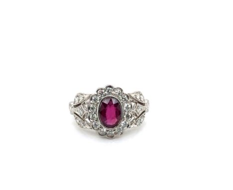 A PLATINUM HALLMARKED RUBY AND DIAMOND CLUSTER RING WITH DIAMOND SET FOLIATE STYLE SHOULDERS. FINGER SIZE M. WEIGHT 8.5grms. 