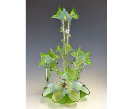 A LATE VICTORIAN GREEN VASELINE GLASS EPERGNE, THE CENTRAL PETAL TOPPED TRUMPET VASE FLANKED BY THREE OTHERS AND THREE BASKET