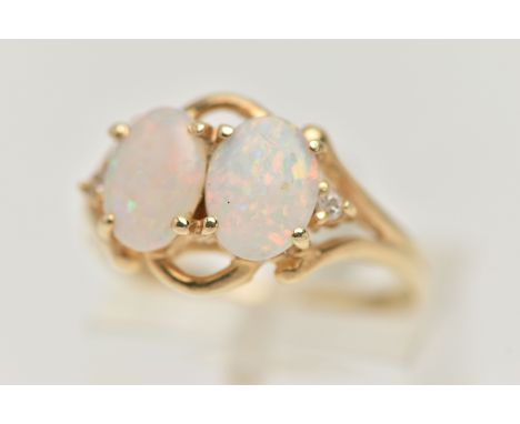 A MODERN YELLOW METAL OPAL AND DIAMOND DRESS RING, set with two oval opal cabochons, claw set, with round brilliant cut diamo